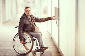 wheelchair user pushes help button at parking place